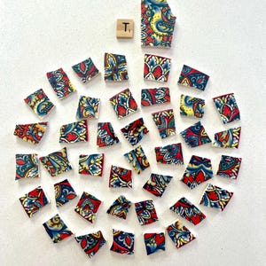 May include: A collection of colorful mosaic tiles arranged in a circular pattern. The tiles feature a red, blue, and yellow floral design. A wooden tile with the letter "T" is also present.