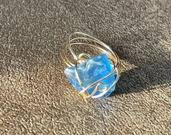 May include: A gold wire ring with a blue crystal stone set in the center.