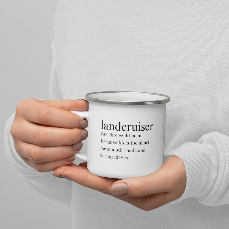 May include: White enamel mug with a black and white graphic that reads "landcruiser (land-kroo-zuh) noun Because life's too short for smooth roads and boring drives."