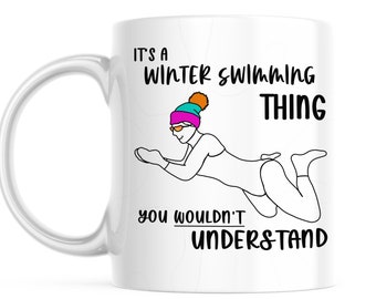 May include: White ceramic mug featuring a black and white illustration of a person wearing a hat and swimming. The text on the mug reads "It's a winter swimming thing you wouldn't understand."