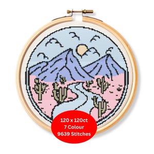 Könnte beinhalten: Ein Kreuzstich-Stickrahmen mit einem Wüstenlandschaftsdesign. Die Szene umfasst Berge, Kakteen, einen Fluss und eine Sonne, alles im Pixelstil. Der Text auf dem roten Kreis lautet: 120 x 120ct, 7 Farben, 9639 Stiche.