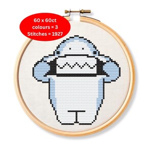 May include: Cross-stitch embroidery of a cartoon character in a wooden hoop. The character is white with light blue accents and black outlines. The text on the image reads: 60 x 60ct, colours = 3, Stitches = 1927.