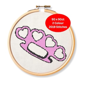 May include: Cross-stitch embroidery in a wooden hoop. The design features a pink, heart-shaped knuckle duster with black outlines. A red circle indicates the piece is 90 x 90ct, 2-color, and 2019 stitches.