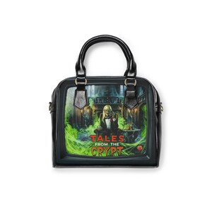 Peut inclure: Un sac à main noir avec une impression graphique du Crypt Keeper de Tales from the Crypt. L'image montre le personnage en smoking assis dans une pièce avec de la brume verte et des toiles d'araignée. Le texte Tales from the Crypt est en rouge et jaune.