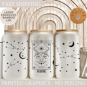 May include: Three frosted glass jars with bamboo lids. Each jar has a different design featuring a constellation, a zodiac sign, and a moon. The jars are labeled with the names "Maddie", "Brynnlee", and "Taurus".