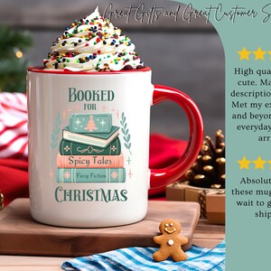 May include: White ceramic mug with a red rim and handle. The mug features a stack of books with the text "Booked for Christmas" and "Spicy Tales" and "Fiery Fiction".