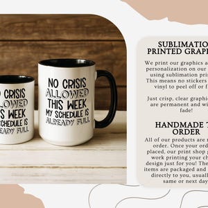 May include: Two white ceramic mugs with black handles and rims. The mugs have the text "NO CRISIS ALLOWED THIS WEEK MY SCHEDULE IS ALREADY FULL" in black. The mugs are on a wooden surface.