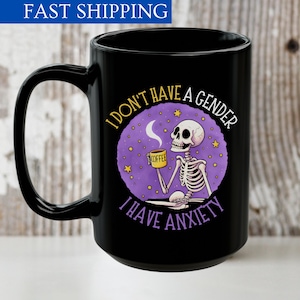 May include: Black coffee mug with a purple and yellow design featuring a skeleton holding a coffee cup. The text on the mug reads "I don't have a gender I have anxiety".