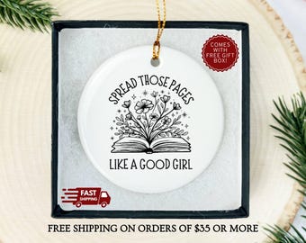 May include: White ceramic ornament with the text "SPREAD THOSE PAGES LIKE A GOOD GIRL" and a floral book design. The ornament is in a black gift box with a gold string for hanging. A red sticker says "COMES WITH FREE GIFT BOX!"