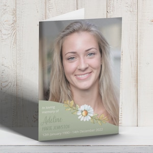 Könnte beinhalten: Eine grüne und weiße Trauerkarte mit einem Foto einer lächelnden Frau. Die Karte hat ein florales Design mit weißen Gänseblümchen und grünen Blättern. Der Text auf der Karte lautet "In liebevoller Erinnerung an Adeline Marie Johnston 12. Januar 1990 - 14. Dezember 2022."