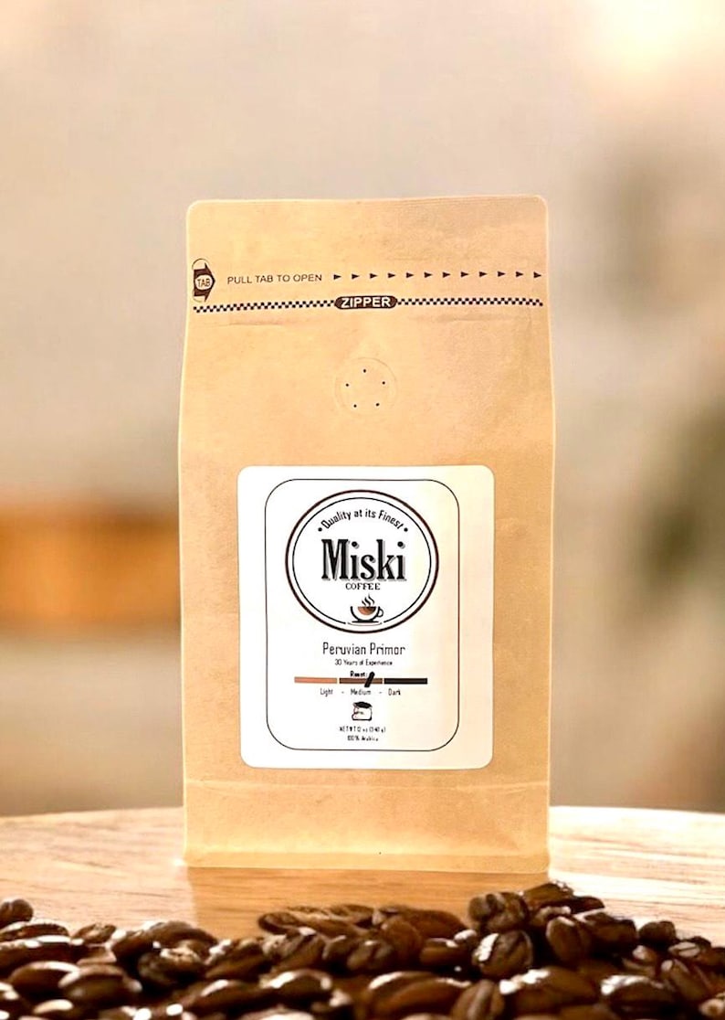 Może przedstawiać: Brązowa papierowa torba z zamkiem błyskawicznym. Torba ma białą etykietę z tekstem "Miski Coffee" i "Peruvian Primor". Etykieta zawiera r&oacute;wnież wskaźnik stopnia palenia z paskiem pokazującym stopień palenia jako "Średni".