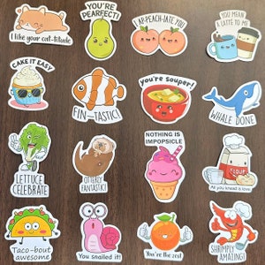 May include: A collection of sixteen die-cut stickers featuring cartoon illustrations of food, animals, and objects with puns. Designs include a cat, pear, peaches, coffee, cupcake, clownfish, soup, whale, lettuce, otter, ice cream, flour, taco, snail, orange, and shrimp.
