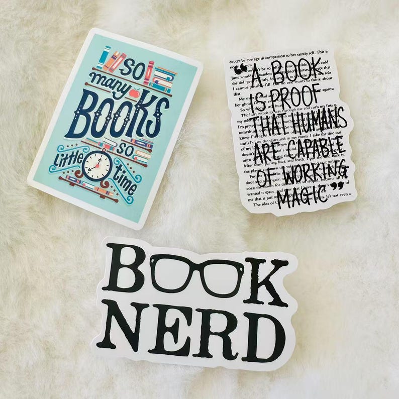 Peut inclure: Trois autocollants rectangulaires et d&eacute;coup&eacute;s. Un autocollant bleu clair pr&eacute;sente des livres color&eacute;s et le texte 'so many BOOKS so little time'. Un autocollant blanc affiche le texte noir 'A BOOK IS PROOF THAT HUMANS ARE CAPABLE OF WORKING MAGIC'. Un autocollant blanc indique 'BOOK NERD' avec des lunettes.