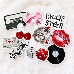 Puede incluir: Una colecci&oacute;n de pegatinas de vinilo que incluye una cinta de casete negra, un lazo rosa, el texto ROCK STAR, un par de cerezas rojas, una bola de discoteca plateada con estrellas rojas, labios rojos, una matr&iacute;cula con 20 SO SPECIAL I LOVE YOU, estrellas negras, dados y un disco.