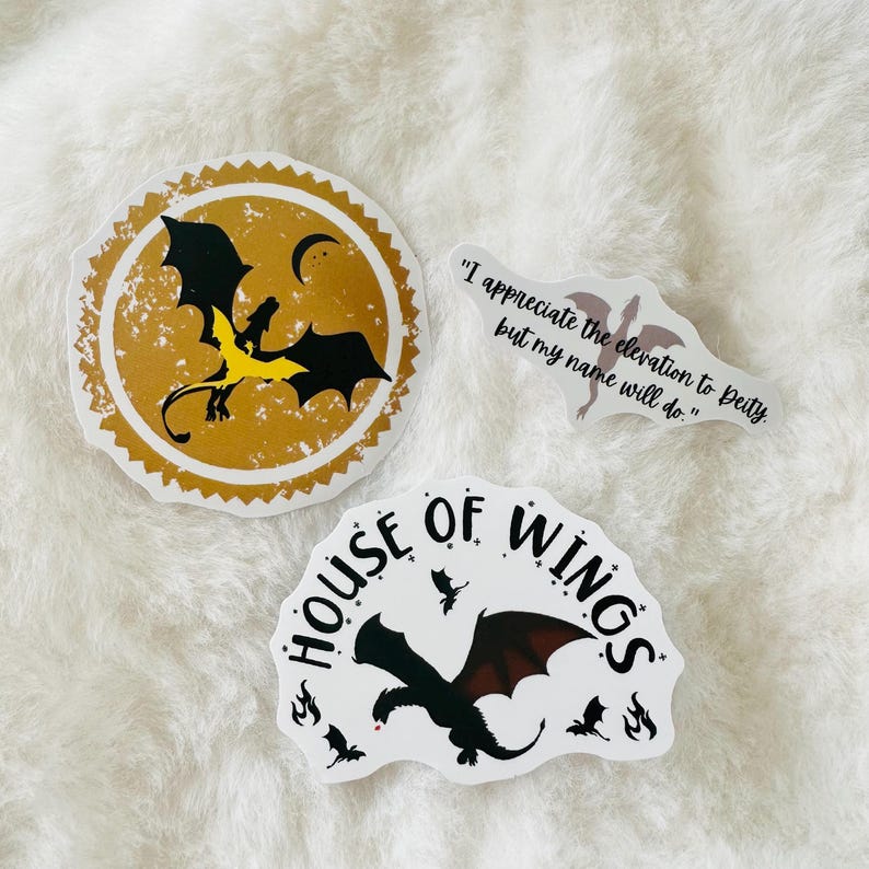 May include: Three stickers featuring dragons. One sticker is gold with a black dragon and the text "House of Wings". Another sticker is white with a black dragon and the text "I appreciate the elevation to Deity, but my name will do."