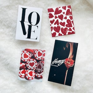 May include: Four rectangular cards featuring distinct designs: one white card with the black text LOVE, one with a red heart pattern, one showing red and white heart-themed poker chips, and one black card with a burning heart and the text Honey ARE U COMING?