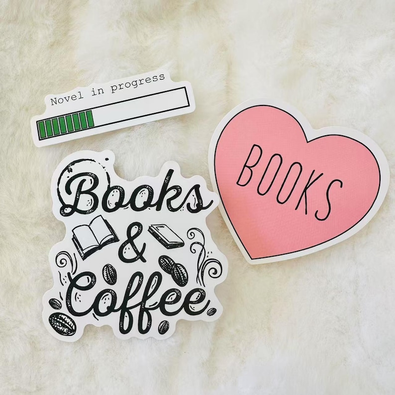 Peut inclure: Trois autocollants aux motifs litt&eacute;raires. L'un est rectangulaire blanc avec le texte Novel in progress et une barre de chargement verte. Un autre est d&eacute;coup&eacute; en blanc avec le texte noir Books & Coffee, des livres et des grains de caf&eacute;. Un autocollant rose en forme de c&oelig;ur avec le mot BOOKS en noir.