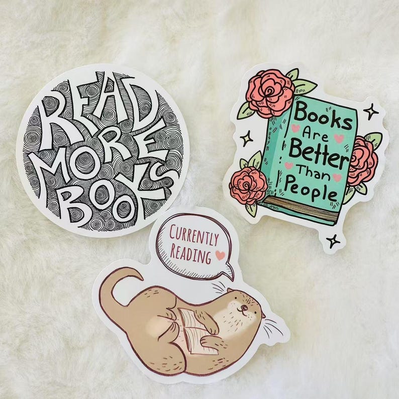 Peut inclure: Trois autocollants en vinyle avec des motifs sur le th&egrave;me des livres. Un autocollant circulaire porte l'inscription READ MORE BOOKS en noir. Un deuxi&egrave;me montre un livre bleu sarcelle avec des roses et le texte Books Are Better Than People.