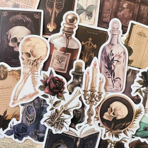 Könnte beinhalten: Eine Sammlung von Stickern im Vintage-Stil mit verschiedenen gruseligen und gotischen Motiven, darunter Schädel, Zaubertrankflaschen, ein Skelett, ein Schmetterling und ein Kandelaber. Die Sticker sind auf weißem Papier mit einem abgenutzten, antiken Look gedruckt.