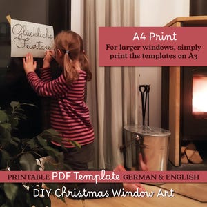 May include: A child in a striped shirt is holding a paper with the words "Gl&uuml;ckliche Feiertage" on a window. The image includes text that says "A4 Print" and "DIY Christmas Window Art". A fireplace and a plant are also visible.