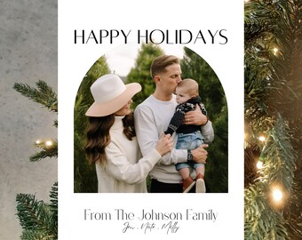 Può includere: Un biglietto di auguri di Natale con una foto di una famiglia di tre persone. I genitori stanno baciando il loro bambino davanti a un albero di Natale. Il biglietto dice "Buon Natale" e "Dalla famiglia Johnson Jen, Nate, Milly".