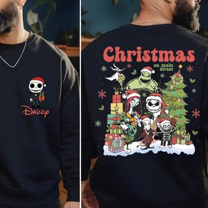 A man wearing a black sweater with a Christmas-themed design on the back.