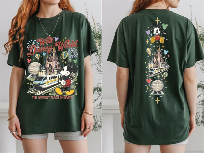 A woman wearing a green t-shirt with a Disney World-themed design, including Mickey Mouse, a castle, and a train.