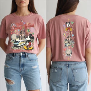 A woman wearing a pink t-shirt with a Disney World theme and various Disney characters and landmarks printed on it.