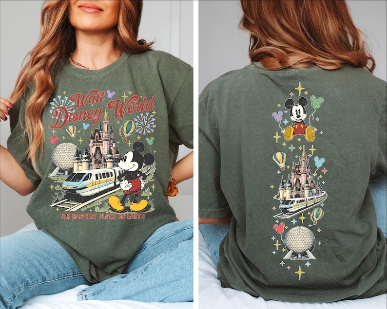 A woman wearing a green t-shirt with a Disney World-themed design, including Mickey Mouse, a castle, and various Disney-related elements.