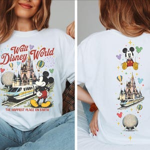 A woman wearing a white t-shirt with a Disney World-themed design, including Mickey Mouse, a castle, and various Disney-related elements.
