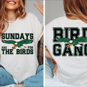 a woman wearing a white shirt with a green bird on it