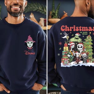 A man wearing a navy blue sweatshirt with a cartoon character on the front and a Christmas-themed design on the back.
