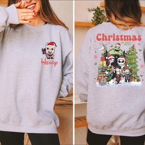 A woman wearing a gray sweatshirt with a Christmas-themed design on the back.