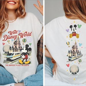 A woman wearing a white t-shirt with a Disney World-themed design, including Mickey Mouse, a castle, and various Disney-themed elements.
