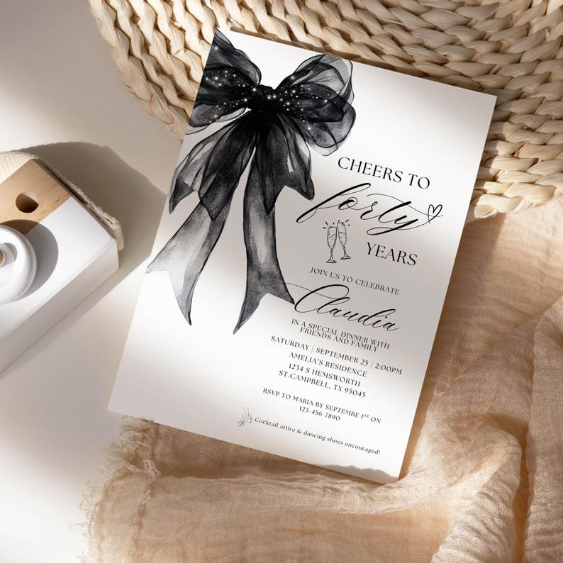 K&ouml;nnte beinhalten: Eine schwarz-wei&szlig;e Einladung mit einer gro&szlig;en schwarzen Schleife mit Glitzer. Die Einladung lautet "Cheers to Forty Years" und "Join us to celebrate Claudia". Die Einladung beschreibt ein besonderes Abendessen mit Freunden und Familie am Samstag, den 25. September um 14:00 Uhr in der Residenz von Amelia, 1234 S Hemsworth, St. Campbell, TX 95045. RSVP an Maria bis zum 1. September unter 123-456 7890. Cocktail-Kleidung und Tanzschuhe sind erw&uuml;nscht.