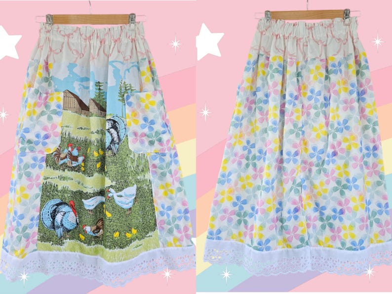 May include: A vintage skirt with a whimsical design. One side features a pastoral scene with turkeys, chickens, and a barn. The other side is covered in colorful floral patterns. The skirt has a white lace trim and pockets.