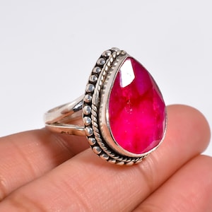 May include: A silver ring with a large, teardrop-shaped pink gemstone set in a beaded bezel.
