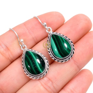 May include: A pair of silver earrings with green malachite gemstone drops. The earrings have a teardrop shape and a silver twisted wire design around the edge of the gemstone.