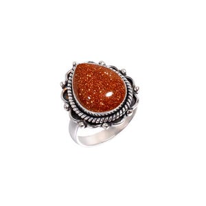 Peut inclure: Bague en argent ornée d'une grosse pierre précieuse dorée-brun étincelante en forme de goutte. La pierre est sertie dans une lunette en argent ornée. L'anneau de la bague est en argent poli simple.