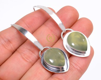 May include: A pair of silver dangle earrings with green gemstone drops. The earrings have a simple, elegant design.