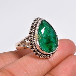 Peut inclure: Une bague en argent sterling avec une émeraude en forme de poire. La bague est ornée d'une bande perlée détaillée et d'une grande émeraude facetée.