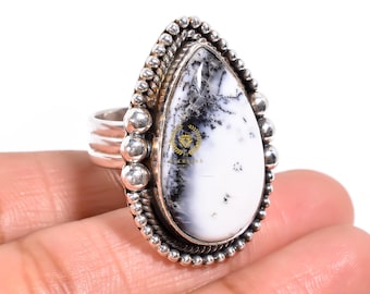 Puede incluir: Anillo de plata con una piedra grande en forma de lágrima. La piedra tiene una base blanca con patrones dendríticos negros. El anillo tiene un engaste de plata detallado con cuentas y acentos decorativos.