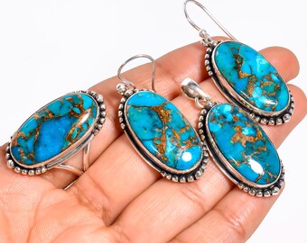 May include: A jewelry set featuring a ring, earrings, and a pendant. Each piece has an oval-shaped, turquoise-colored stone with copper-colored veining, set in a silver-colored metal with a beaded border. The earrings have a hook closure.