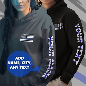 May include: Two hooded sweatshirts with a thin blue line American flag design. One sweatshirt has the flag on the front and the other has the flag on the sleeve with the text "YOUR NAME" printed on the sleeve.
