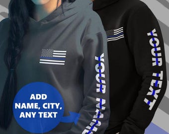 Pode incluir: Duas blusas de frio com capuz com um design de bandeira americana de linha azul fina. Uma blusa de frio tem a bandeira na frente e a outra tem a bandeira na manga com o texto "YOUR NAME" impresso na manga.