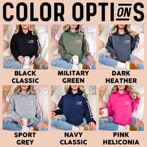 May include: Six different color options for a hooded sweatshirt with a small American flag on the front and a larger American flag on the sleeve. The colors are black, military green, dark heather, sport grey, navy, and pink.