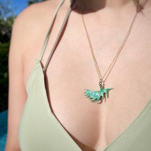 May include: A gold chain necklace with a green antler pendant. The pendant is a detailed, stylized antler with a green enamel finish.