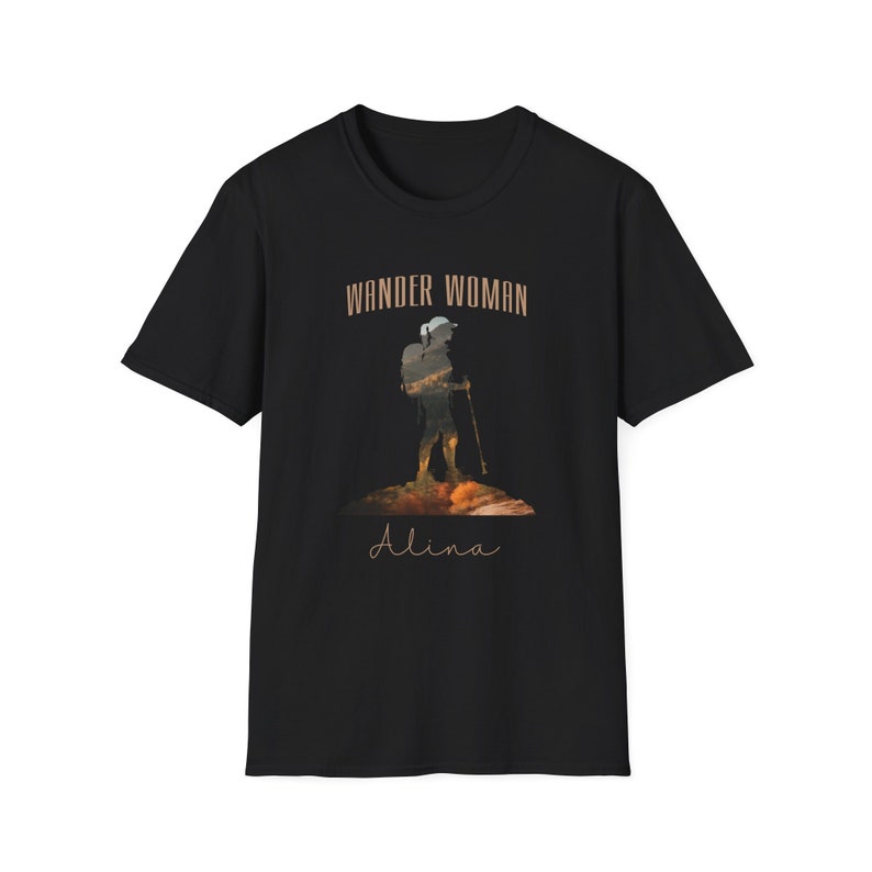 Puede incluir: Camiseta negra con un gr&aacute;fico marr&oacute;n de un excursionista con una mochila y el texto "Wander Woman" sobre el gr&aacute;fico y "Alina" debajo del gr&aacute;fico.