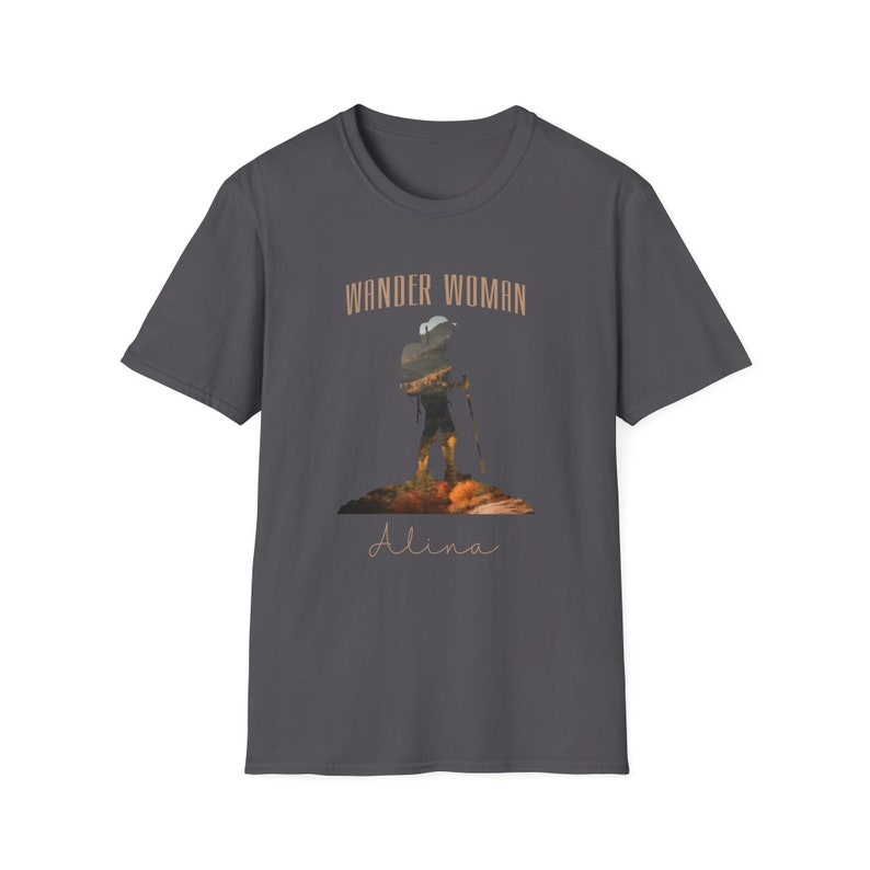 Puede incluir: Una camiseta gris oscuro con la silueta de un excursionista con una mochila y bastones de senderismo. El texto "Wander Woman" est&aacute; por encima del excursionista y el nombre "Alina" est&aacute; por debajo del excursionista.