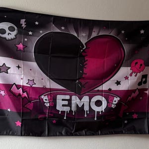 Könnte beinhalten: Schwarz-weiß-rosa Flagge mit Emo-Thema. Die Flagge zeigt ein genähtes Herzdesign, Sterne, einen Totenkopf und das Wort "EMO" in weißen, tropfenden Buchstaben. Die Flagge ist rechteckig und aus Stoff.